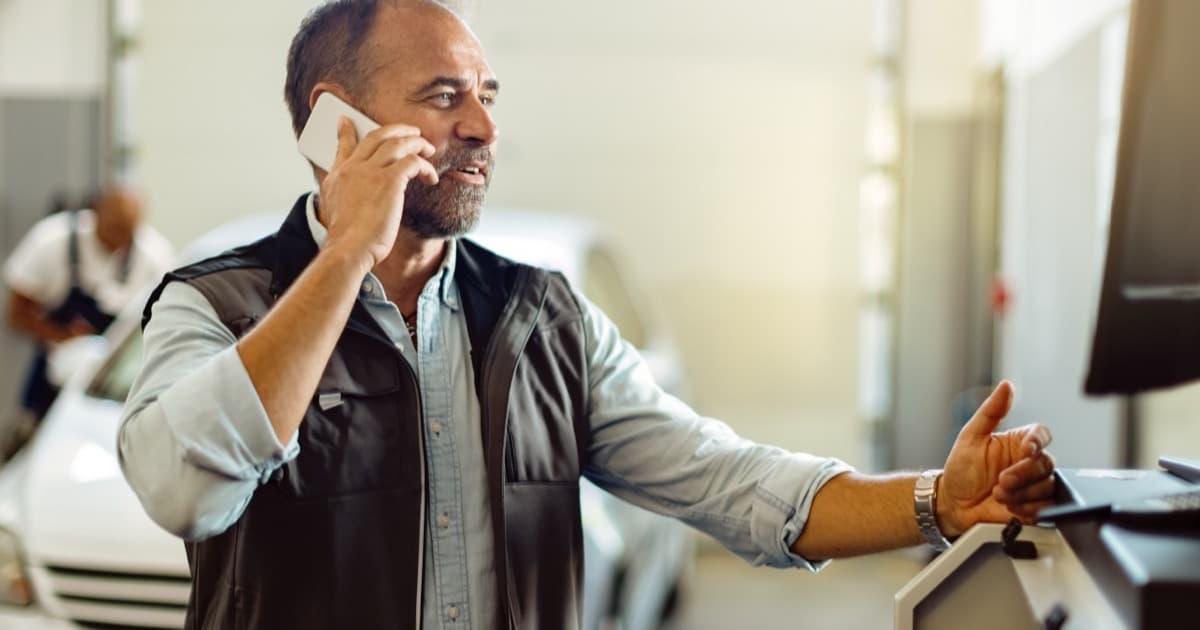 Mecânico atendendo cliente ao telefone na oficina