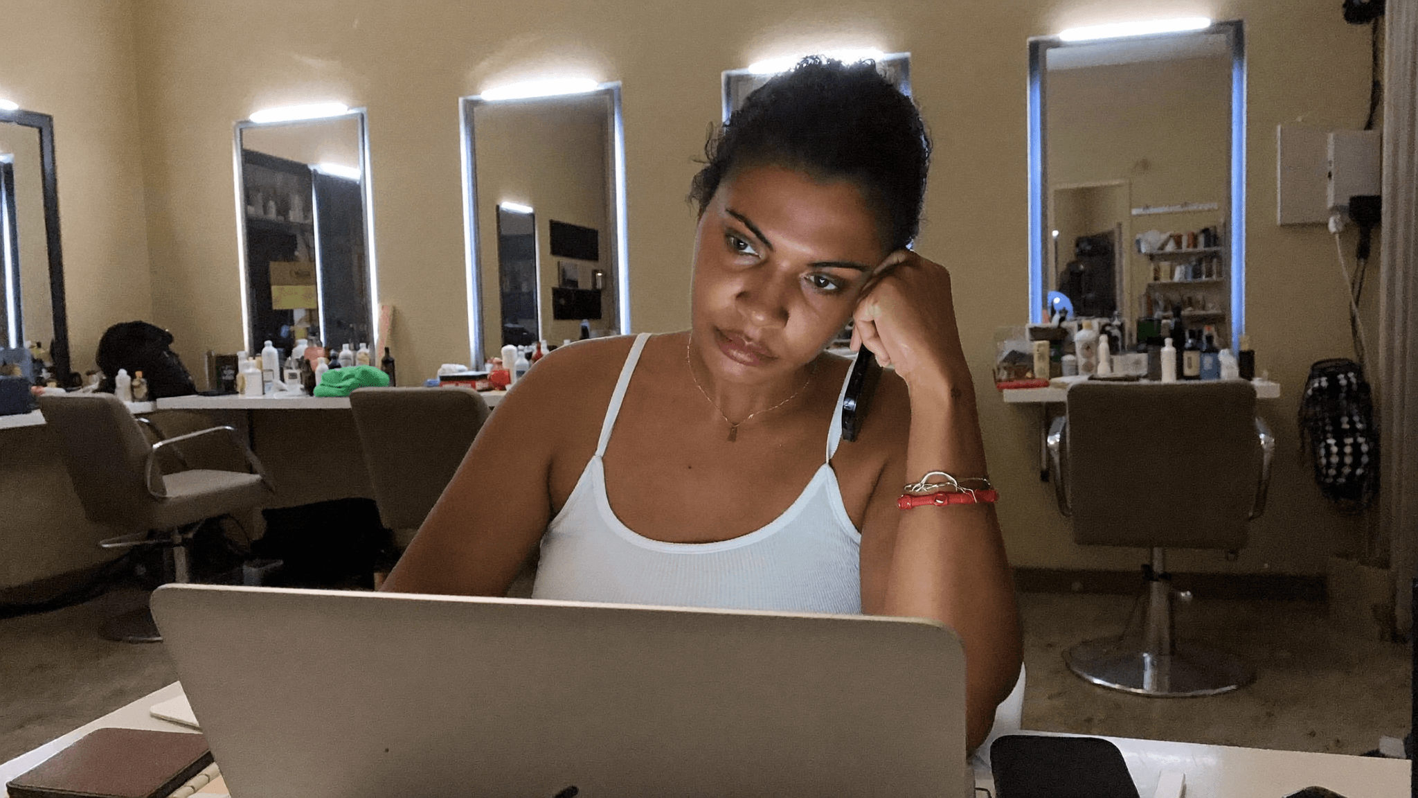 Dona de salão de beleza comparando opções de chatbot gratuito no notebook após o expediente